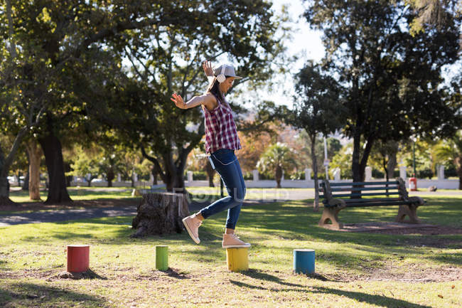 Женщина балансирует на красочных пнях в парке в солнечный день — стоковое фото