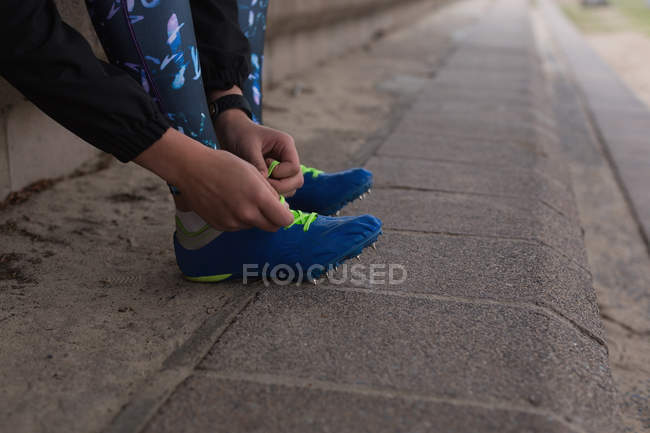 Atleta donna allacciatura lacci delle scarpe presso la sede sportiva — Foto stock