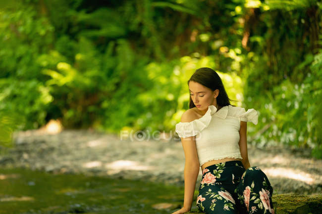 Красива жінка сидить у зеленому лісі — стокове фото