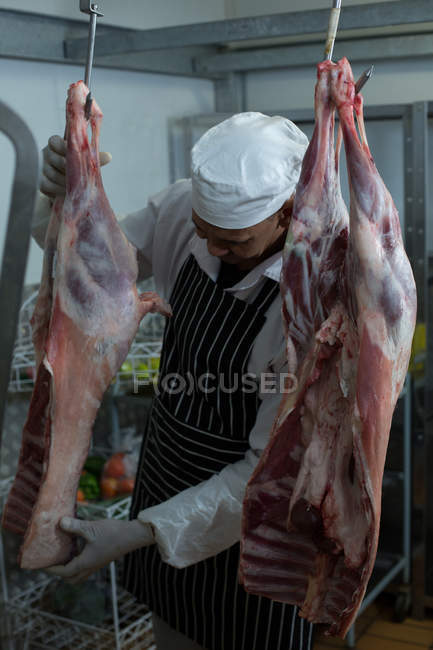Мясник держит свежее мясо в мясной лавке — стоковое фото