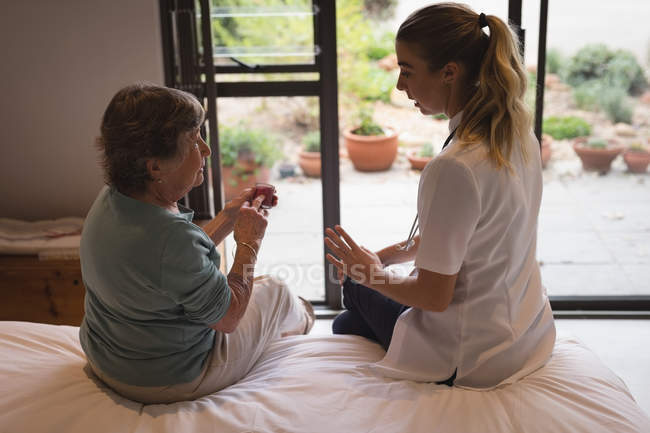 Fisioterapeuta discutindo com uma mulher idosa em casa — Fotografia de Stock