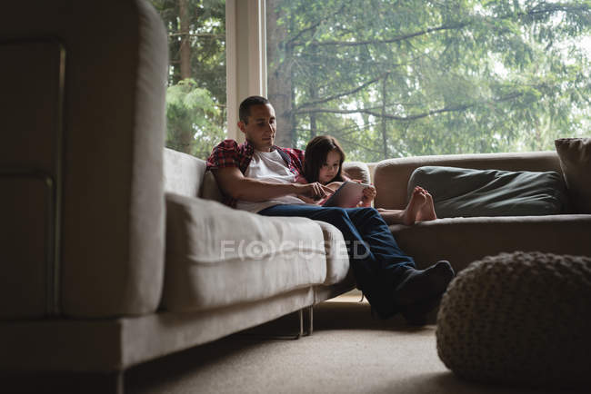 Отец и дочь используют цифровой планшет в гостиной на дому — стоковое фото