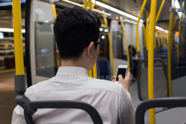 Вид ззаду людини, що використовує мобільний телефон під час подорожі в поїзді — стокове фото