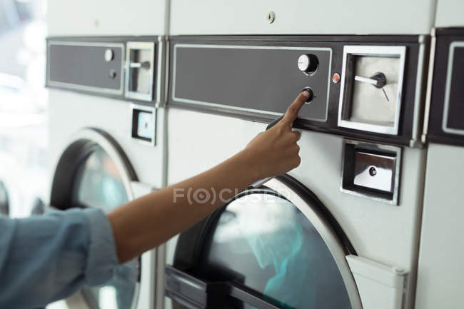 Close-up de mulher operando máquina de lavar roupa na lavanderia — Fotografia de Stock