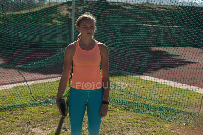 Женщина-атлет, практикующая метание диска на спортивном объекте — стоковое фото