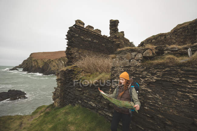 Красива жінка мандрівного притулившись скелі і читання карті — стокове фото