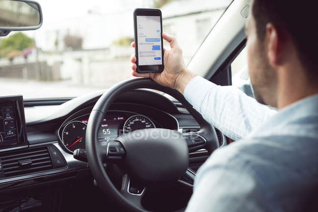 Бизнесмен, использующий мобильный телефон в современном автомобиле — стоковое фото