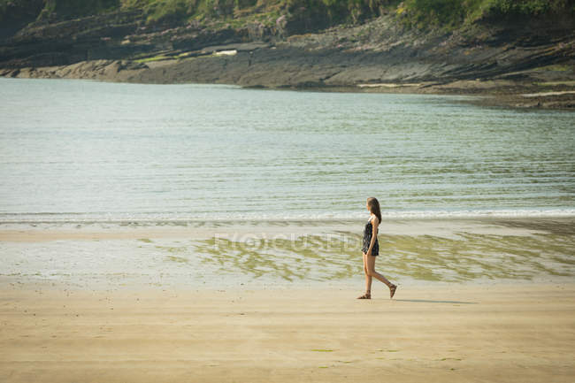 Женщина гуляла по пляжу в солнечный день — стоковое фото
