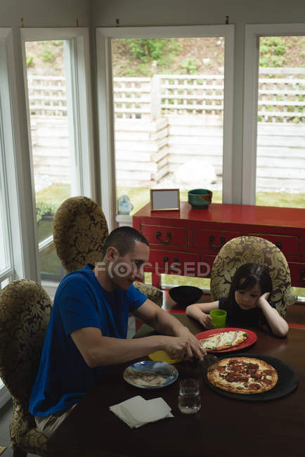 Отец и дочь едят вместе пиццу дома — стоковое фото