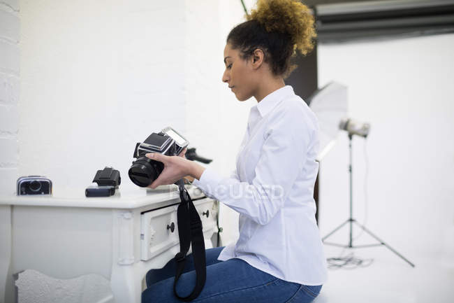 Fotografo femminile rimuovere bobina dalla fotocamera digitale in studio fotografico — Foto stock