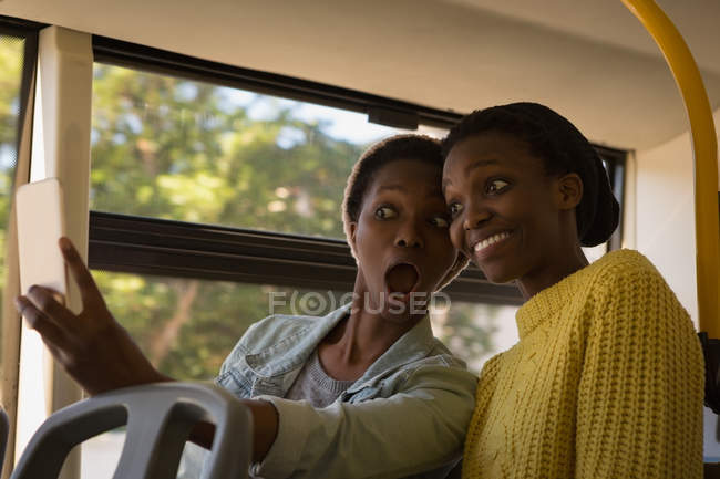 Gemelos hermanos tomando selfie con teléfono móvil en el autobús - foto de stock