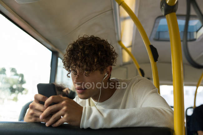 Junger Mann hört während Busfahrt Musik auf Handy — Stockfoto