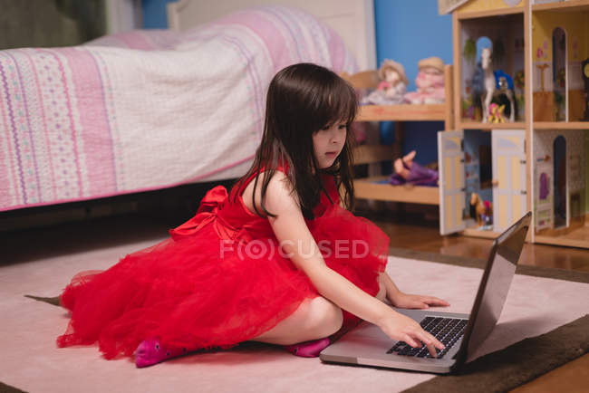 Fille en utilisant ordinateur portable dans la chambre à coucher à la maison — Photo de stock