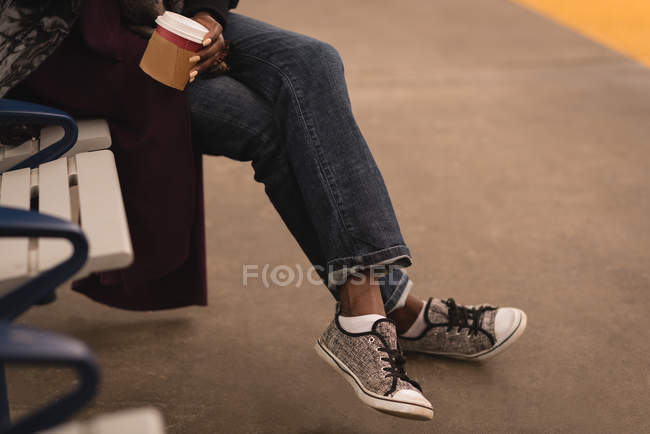 Низька частина жінки, яка має каву на залізничній станції — стокове фото