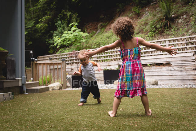 Братья и сестры играют в саду в солнечный день — стоковое фото