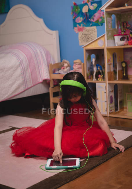 Girl listening music on digital tablet in bedroom at home — Stock Photo