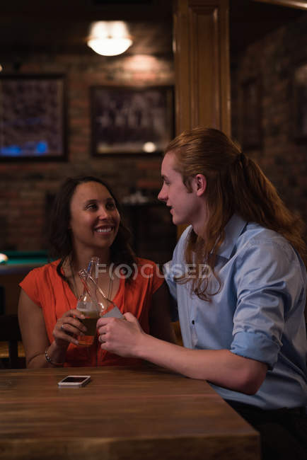 Happy couple toasting beer bottles in the night club — Stock Photo