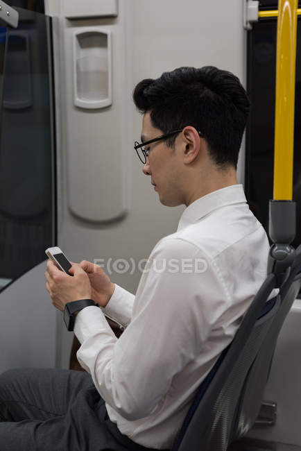 Joven usando teléfono móvil mientras viaja en tren - foto de stock
