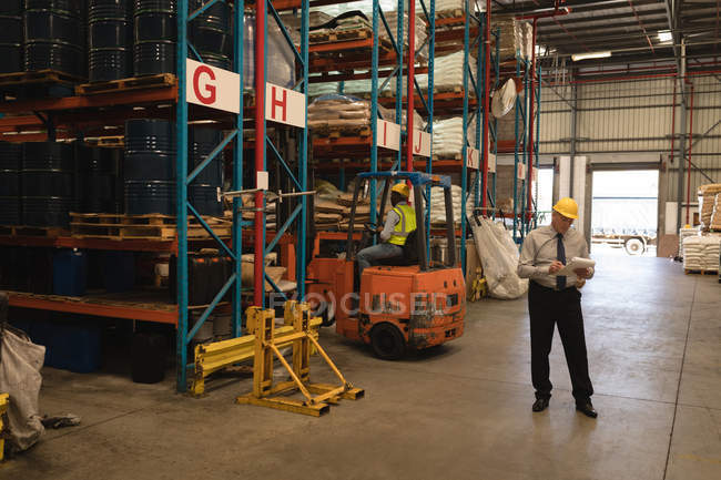 Gestionnaire masculin tenant une comptabilité matières en entrepôt — Photo de stock