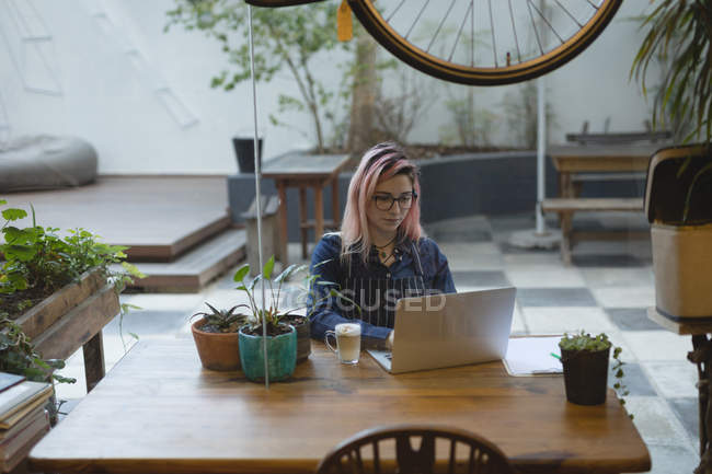 Giovane donna che usa un portatile alla caffetteria — Foto stock