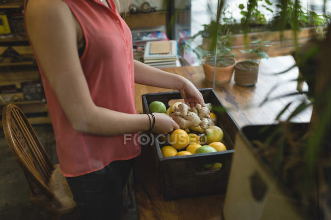 Mujer joven sacando vegetales de la bandeja - foto de stock