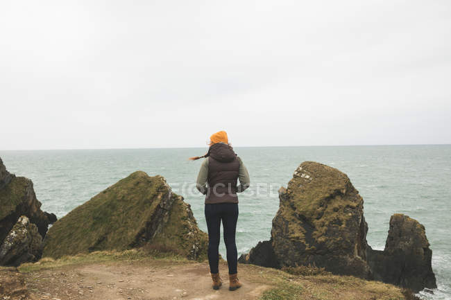 Туристка с видом сзади смотрит на красивое море — стоковое фото