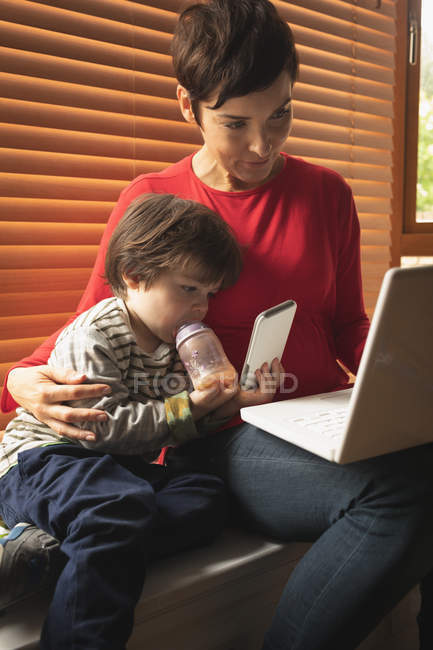 Primo piano madre e figlio seduti con un computer portatile a casa — Foto stock