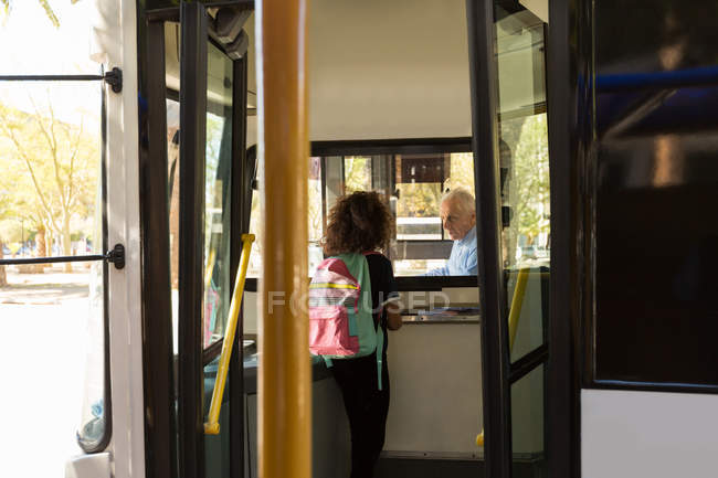 Дівчина-підліток взаємодіє з водієм автобуса — стокове фото