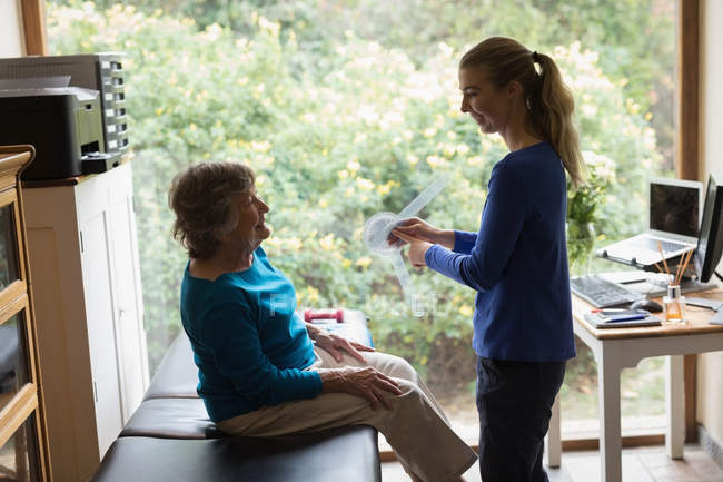 Физиотерапевт показывает чтение гониометра пожилой женщине — стоковое фото