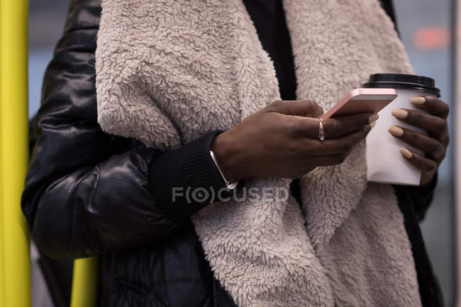 Mid section of woman using mobile phone in metro train — Stock Photo