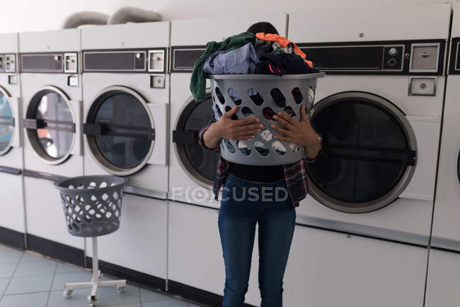 Woman carrying laundry basket at laundromat — Stock Photo