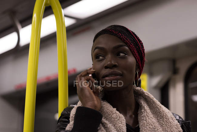 Молодая женщина разговаривает по мобильному телефону во время поездки на поезде — стоковое фото