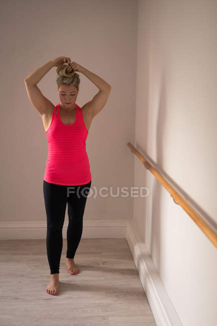 Mulher de pé com as mãos no cabelo no estúdio de fitness — Fotografia de Stock