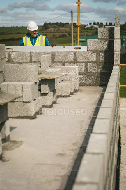 Ingeniero haciendo una comprobación de nivel en la pared en el sitio de construcción - foto de stock