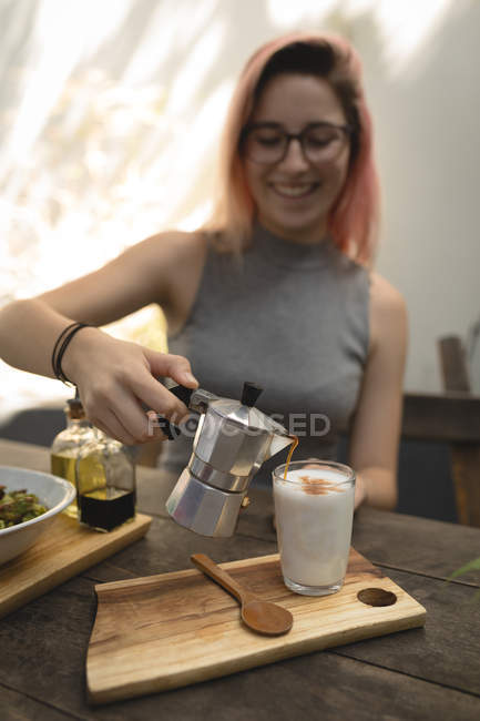 Jovem mulher derramando café de uma chaleira de café — Fotografia de Stock