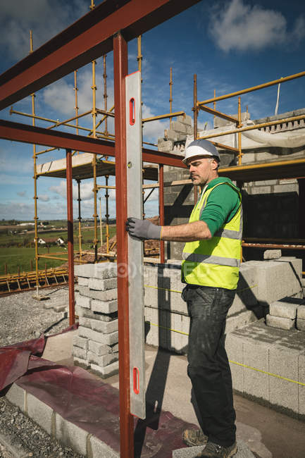 Engineer with level gauge working at the construction site on a sunny day — Stock Photo