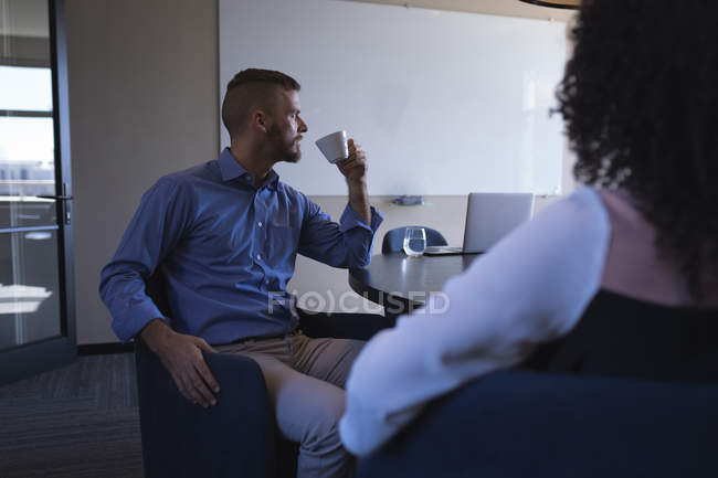Business executives sitting and discussing while having coffee at office — Stock Photo