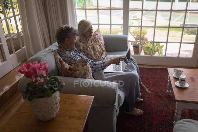 Seniorenpaar benutzt Laptop auf Sofa zu Hause — Stockfoto