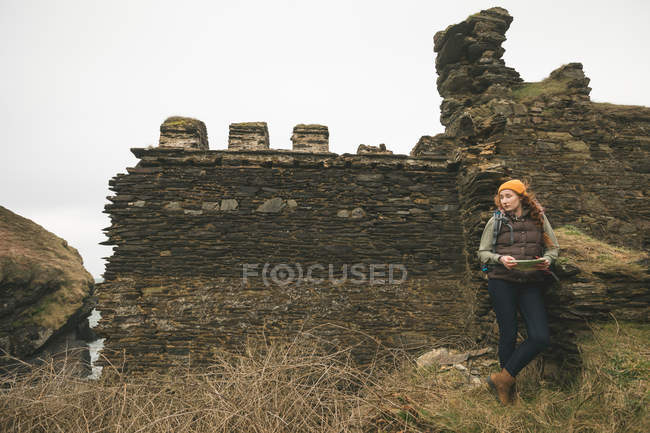 Hermosa excursionista femenina con mapa mirando hacia los lados - foto de stock