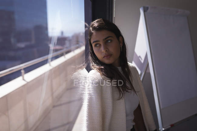 Ragionevole donna d'affari guardando fuori dalla finestra in ufficio — Foto stock