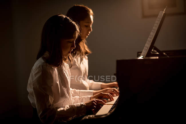 Siblings playing together piano in music school — Stock Photo