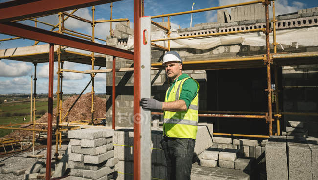 Ingenieur mit Pegel arbeitet an einem sonnigen Tag auf der Baustelle — Stockfoto