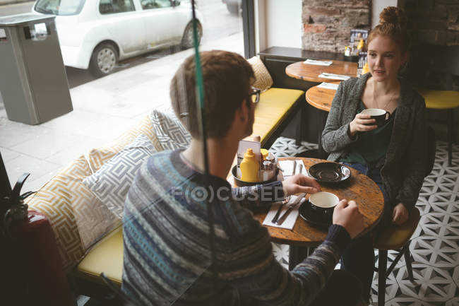 Pareja joven hablando sobre el café en la cafetería - foto de stock