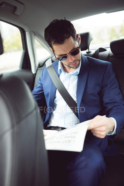 Smart businessman reading newspaper in a car — Stock Photo