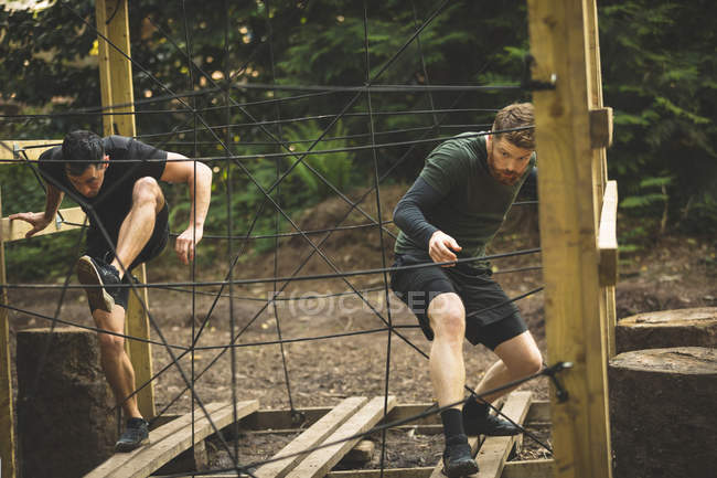 Deux hommes s'entraînent sur un parcours d'obstacles au camp d'entraînement — Photo de stock