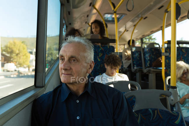Старший мужчина смотрит в окно во время путешествия в автобусе — стоковое фото
