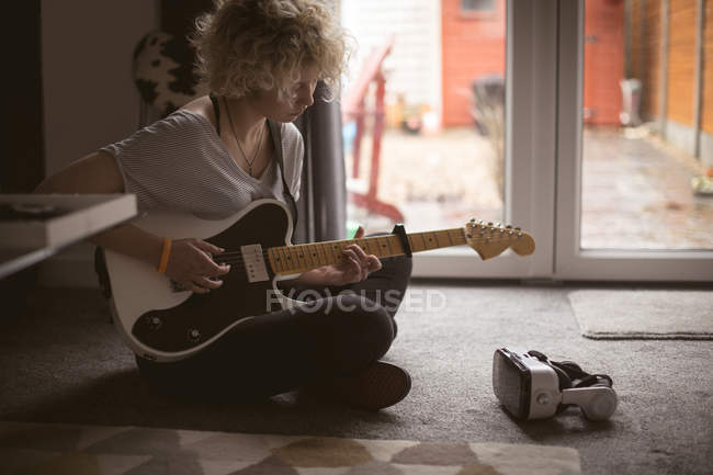 Jovem tocando guitarra na sala de estar em casa — Fotografia de Stock