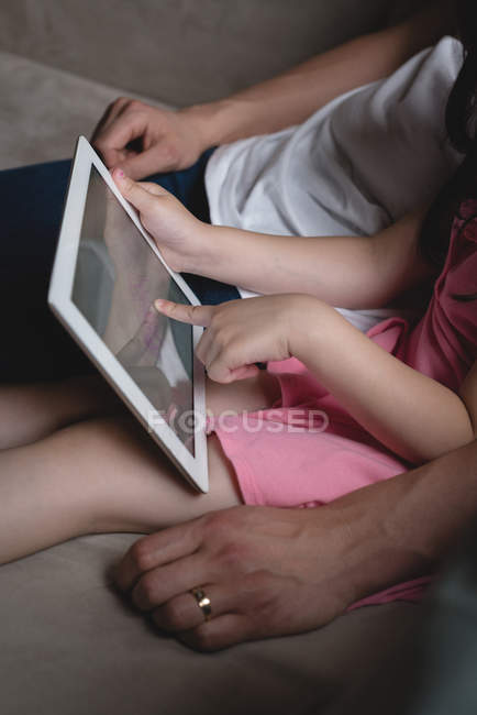 Seção média de pai e filha usando tablet digital na sala de estar em casa — Fotografia de Stock