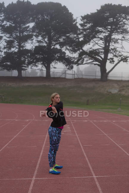 Atleta femenina calentándose en pista de atletismo - foto de stock