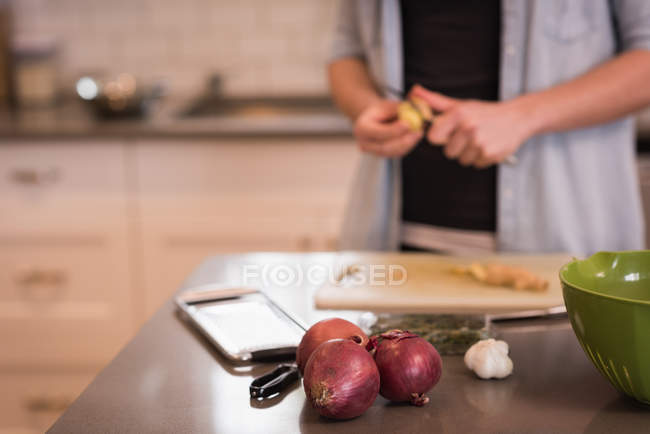 Mid section of woman cutting vegetables in kitchen at home — Stock Photo